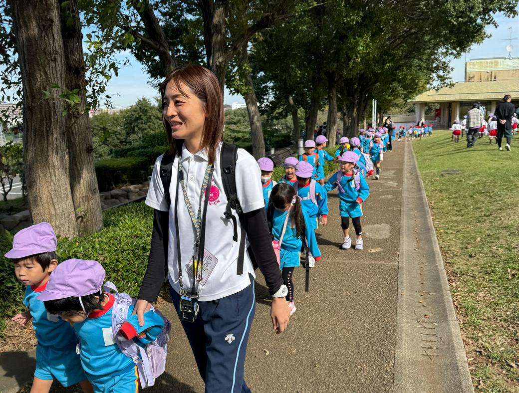 並木道を先生と歩く園児たち