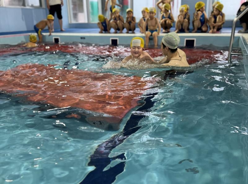 室内温水プールで泳ぐ園児