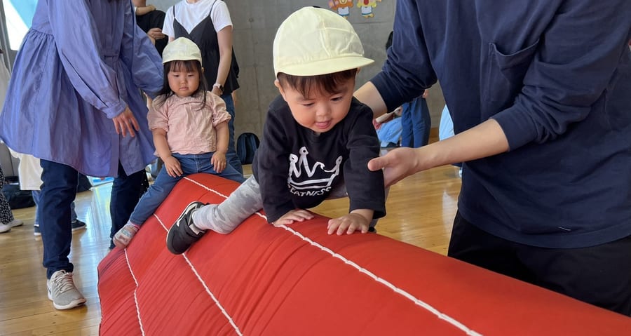 ホールで保護者や先生に見守られながら体を動かす子ども