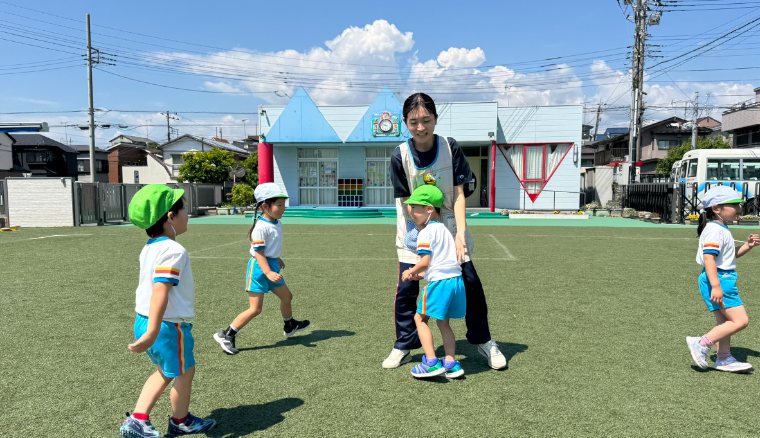 青空の園庭で子どもに寄り添う先生