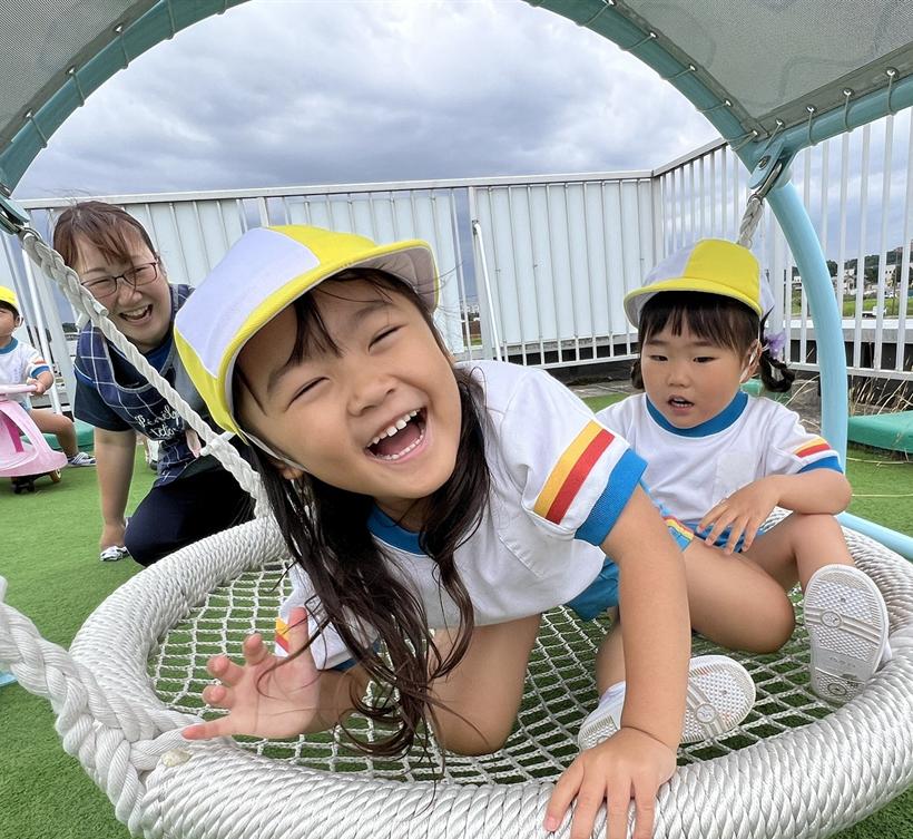 丸いネットの遊具で笑う園児たち